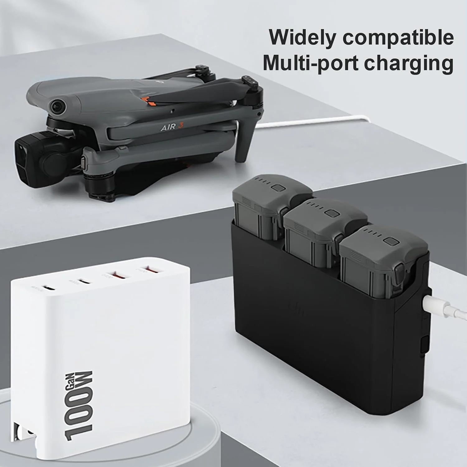 A multi-port 100W GaN charger simultaneously supplying power to a folded DJI Air 3 drone and a three-slot drone battery charging hub